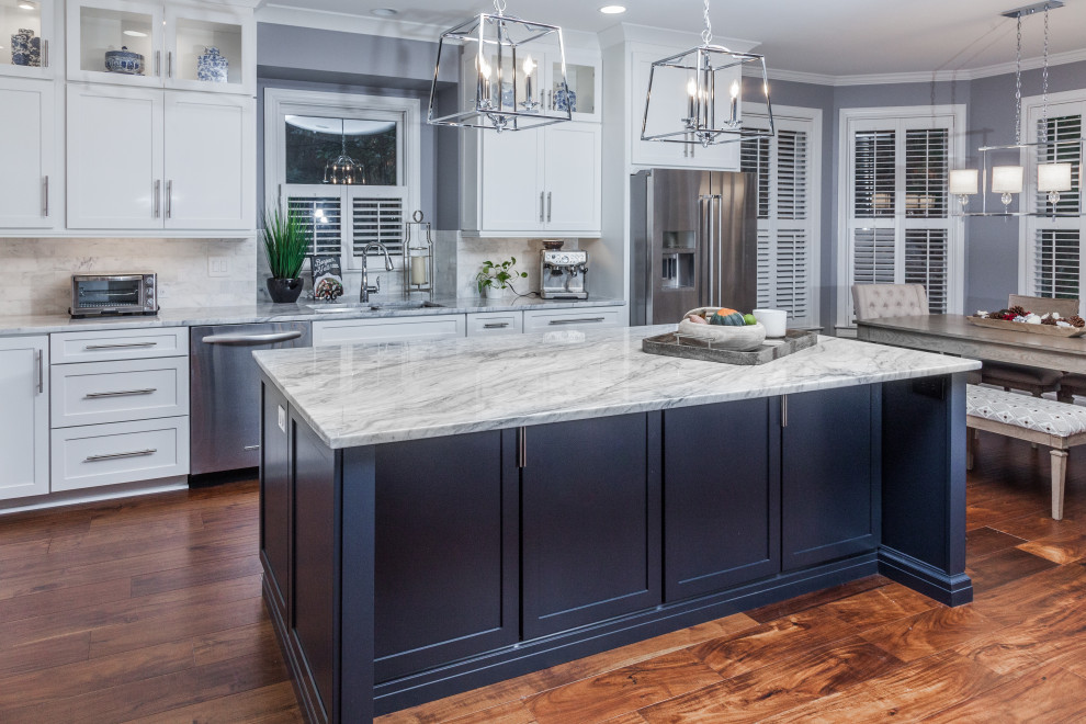 Photo of an expansive traditional eat-in kitchen in Atlanta with a double-bowl sink, shaker cabinets, blue cabinets, quartzite benchtops, white splashback, marble splashback, stainless steel appliances, medium hardwood floors, with island and white benchtop.