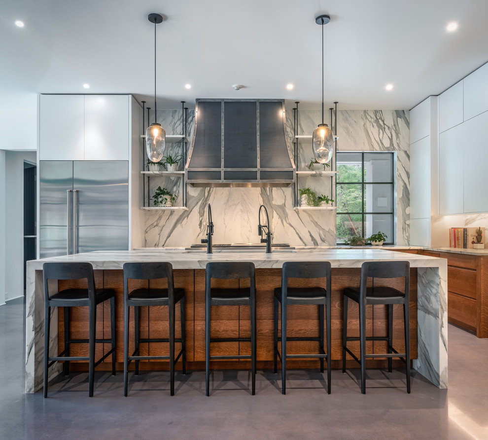 Inspiration for a concrete floor and gray floor kitchen remodel with an undermount sink, flat-panel cabinets, medium tone wood cabinets, marble countertops, gray backsplash, marble backsplash, stainless steel appliances, an island and gray countertops