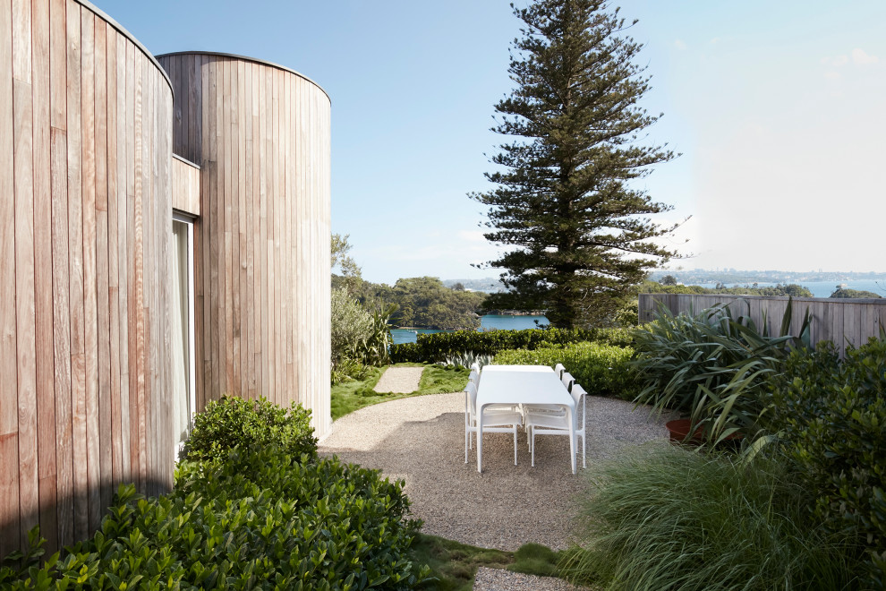 Immagine di un giardino minimalista esposto a mezz'ombra con ghiaia e recinzione in legno