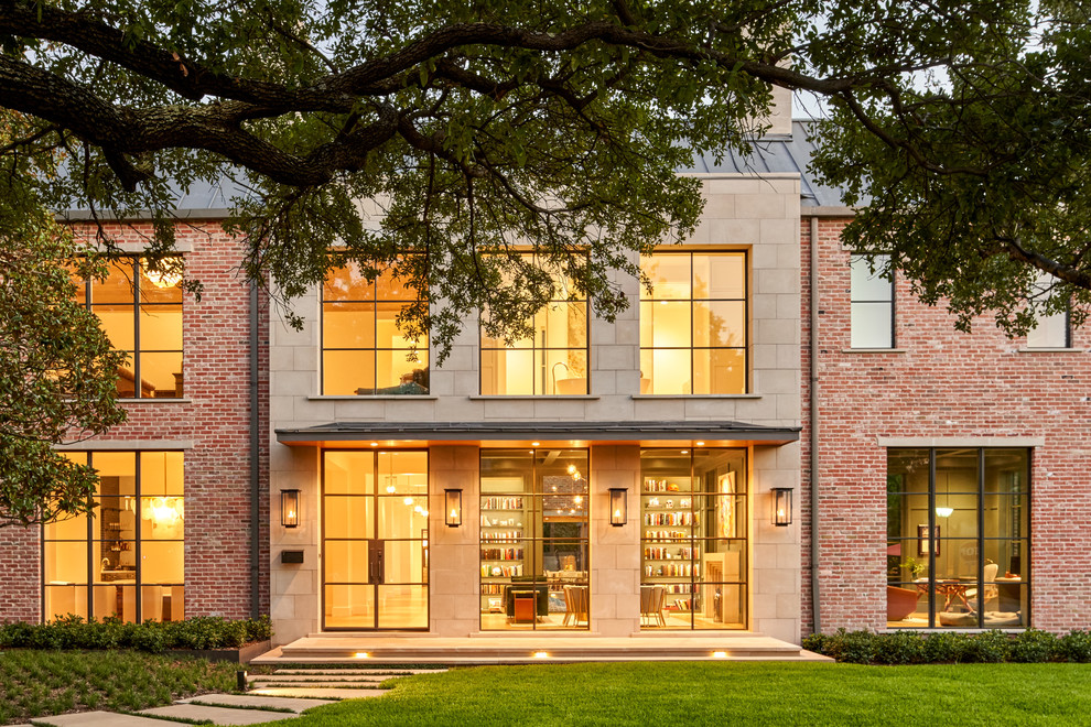 This is an example of a large transitional two-storey brick brown house exterior in Dallas with a gable roof and a metal roof.