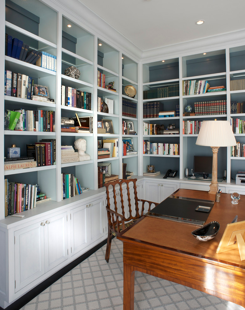 Design ideas for a mid-sized traditional home office in New York with a library, blue walls, dark hardwood floors, no fireplace, a freestanding desk and brown floor.