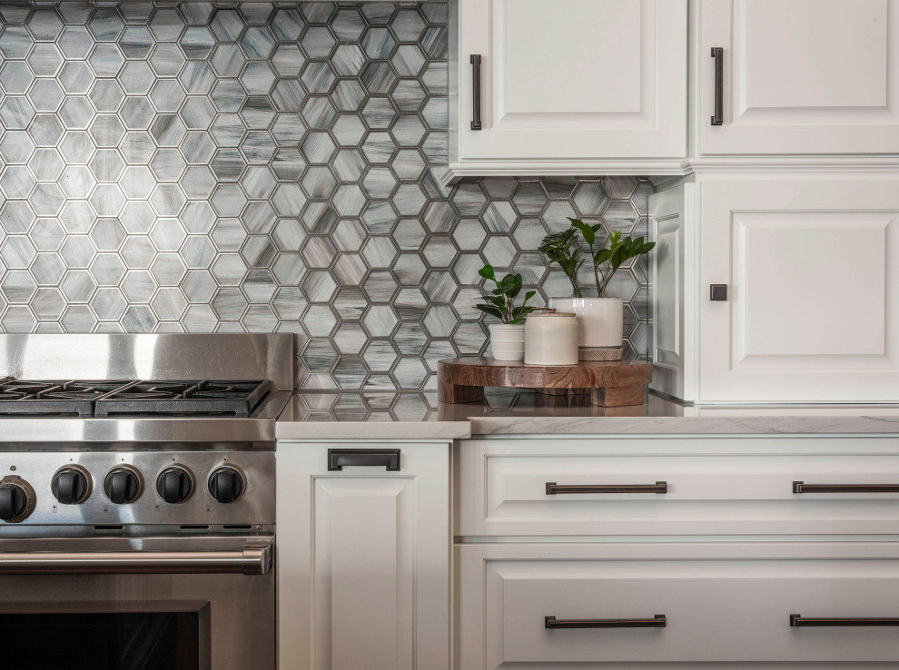 Example of an eclectic medium tone wood floor, brown floor and exposed beam open concept kitchen design in Orlando with a farmhouse sink, recessed-panel cabinets, white cabinets, quartzite countertops, gray backsplash, mosaic tile backsplash, paneled appliances, an island and white countertops