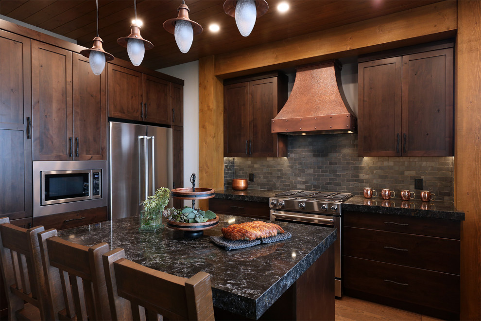 Foto på ett rustikt svart kök med öppen planlösning, med en rustik diskho, skåp i shakerstil, skåp i mellenmörkt trä, bänkskiva i kvartsit, svart stänkskydd, stänkskydd i skiffer, rostfria vitvaror, mellanmörkt trägolv, en köksö och brunt golv