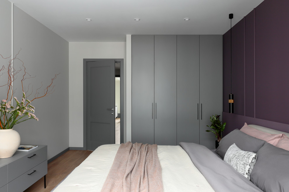Cette image montre une chambre design de taille moyenne avec un mur violet, un sol en bois brun et un sol marron.