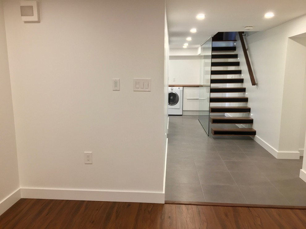 Photo of a midcentury look-out basement in Toronto with white walls, ceramic floors and grey floor.