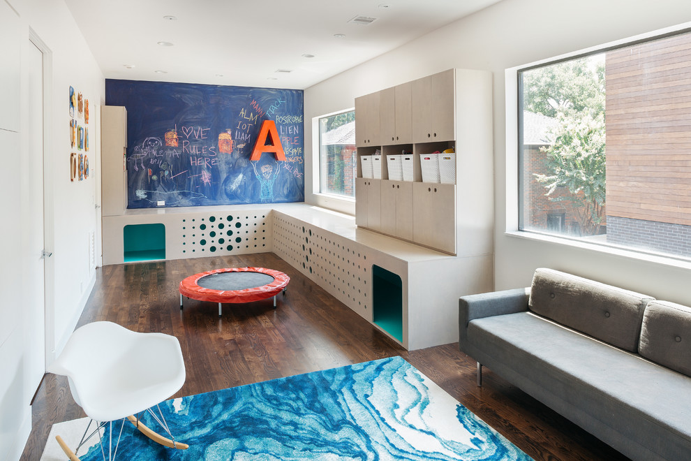 This is an example of a contemporary gender-neutral kids' playroom in Houston with white walls and dark hardwood floors.