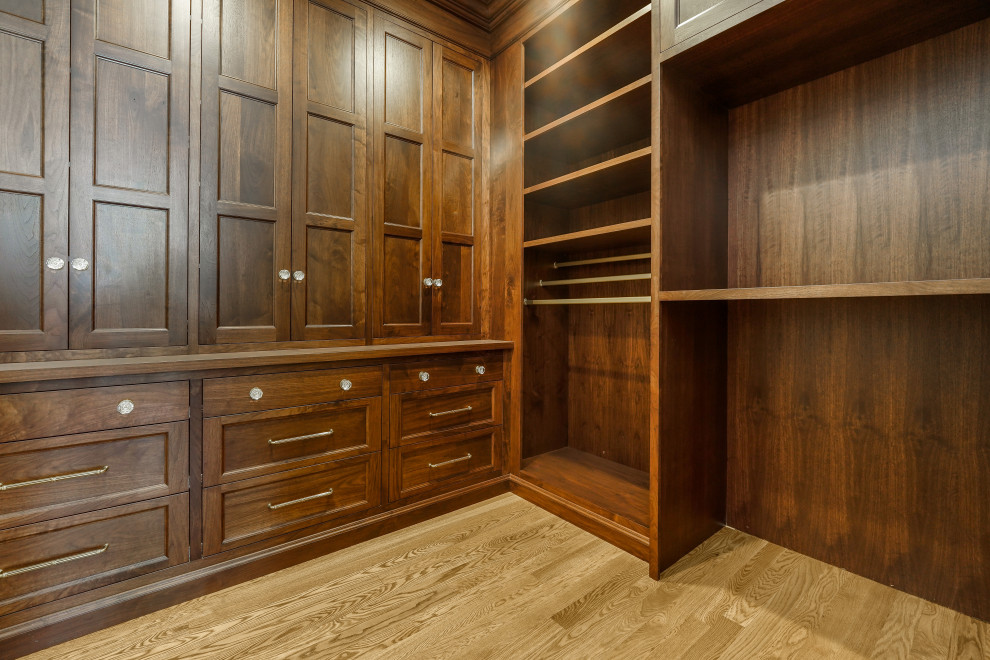 Photo of an expansive walk-in wardrobe in Salt Lake City with recessed-panel cabinets, dark wood cabinets, medium hardwood floors and brown floor.