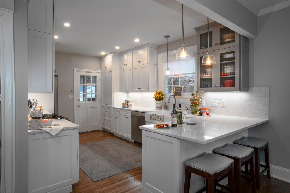 Photo of a mid-sized country l-shaped eat-in kitchen in Other with a farmhouse sink, shaker cabinets, white cabinets, quartz benchtops, white splashback, subway tile splashback, stainless steel appliances, light hardwood floors, no island and white benchtop.
