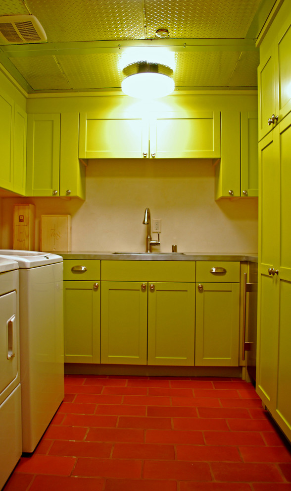 Inspiration for a mid-sized eclectic u-shaped dedicated laundry room in Albuquerque with an undermount sink, raised-panel cabinets, green cabinets, stainless steel benchtops, white walls, terra-cotta floors and a side-by-side washer and dryer.