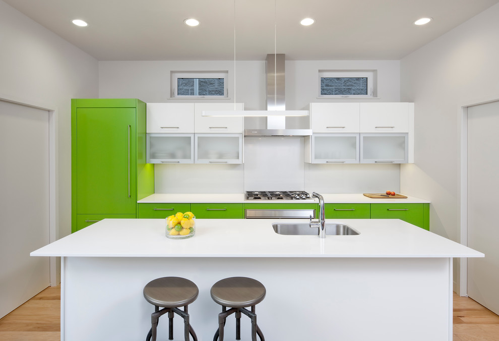 Inspiration for a contemporary galley kitchen in Chicago with a single-bowl sink, flat-panel cabinets, quartz benchtops, glass sheet splashback, stainless steel appliances, with island, green cabinets and light hardwood floors.
