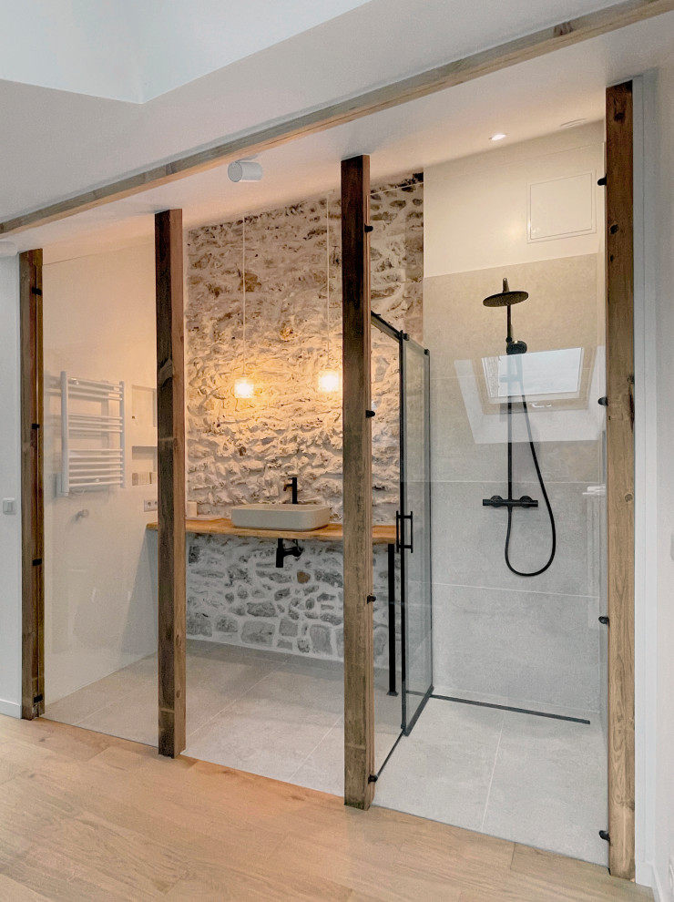 Cette photo montre une salle de bain blanche et bois scandinave avec une douche à l'italienne, des carreaux de céramique, un sol en carrelage de céramique, un plan de toilette en bois et un mur en pierre.