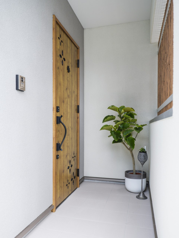 Cette image montre une entrée minimaliste de taille moyenne avec un mur blanc, une porte simple et une porte marron.