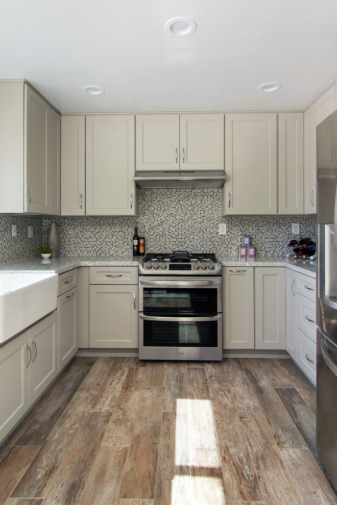 This is an example of a mid-sized transitional u-shaped eat-in kitchen in San Diego with a farmhouse sink, shaker cabinets, grey cabinets, quartz benchtops, multi-coloured splashback, mosaic tile splashback, stainless steel appliances, porcelain floors, no island, grey floor and multi-coloured benchtop.