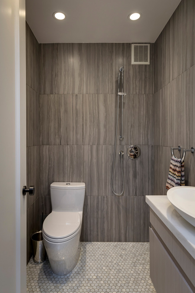 This is an example of a contemporary wet room bathroom in New York with flat-panel cabinets, grey cabinets, a one-piece toilet, gray tile, mosaic tile floors, a vessel sink, white floor and an open shower.