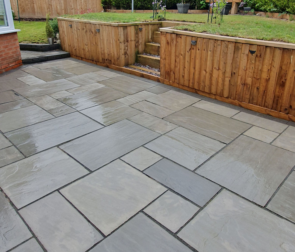 This is an example of a medium sized classic back patio in Hertfordshire with natural stone paving.