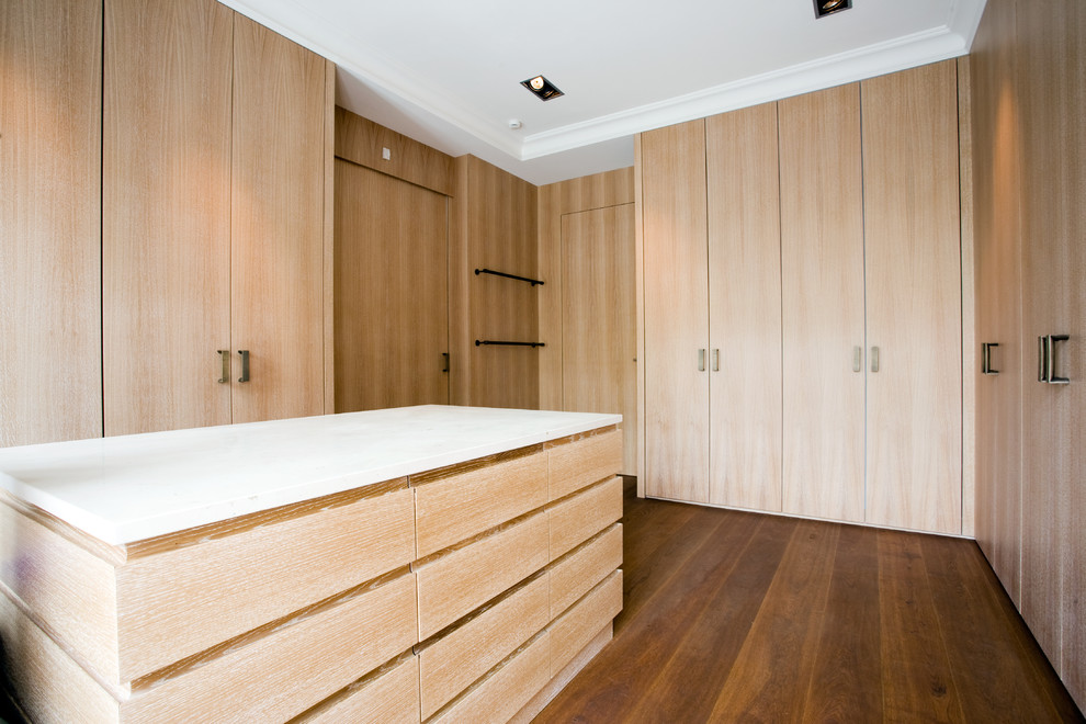 This is an example of an expansive contemporary gender-neutral dressing room in Hamburg with flat-panel cabinets, medium hardwood floors, brown floor and light wood cabinets.