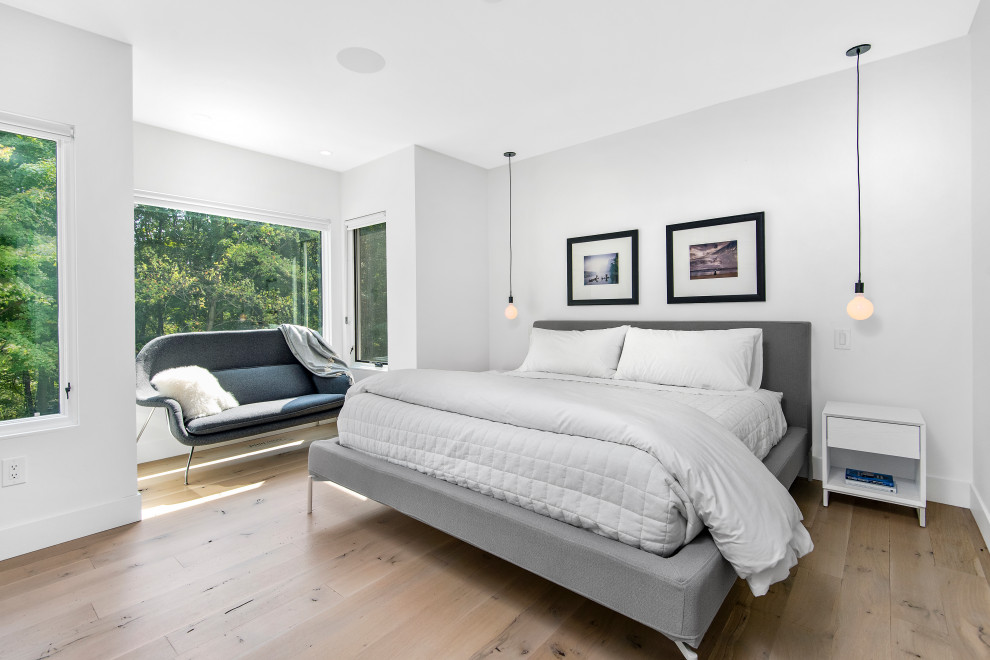 Modern master bedroom in Chicago with white walls, light hardwood floors and beige floor.