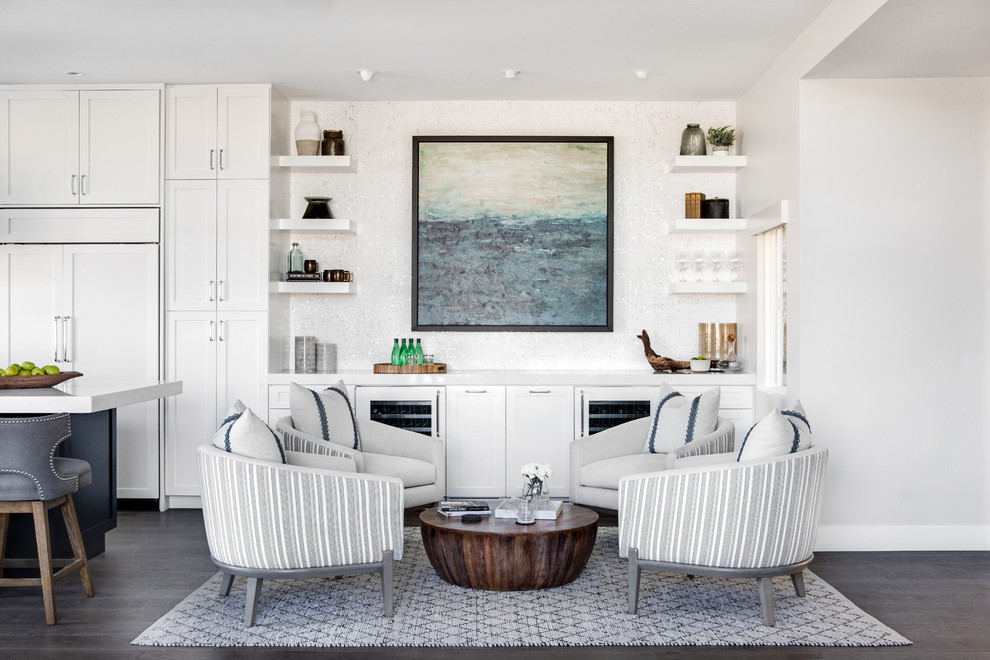 This is an example of a mid-sized beach style open concept living room in Los Angeles with a home bar, white walls, a standard fireplace, a stone fireplace surround, medium hardwood floors and brown floor.