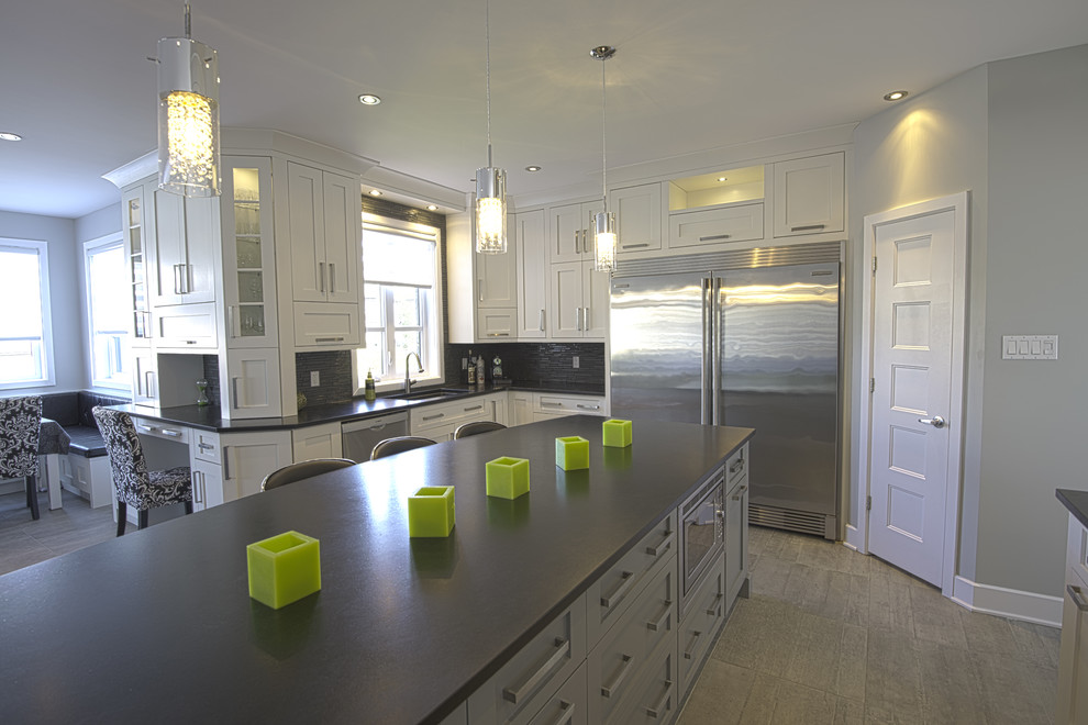This is an example of a large contemporary u-shaped eat-in kitchen in Montreal with an undermount sink, shaker cabinets, white cabinets, quartzite benchtops, black splashback, matchstick tile splashback, stainless steel appliances, vinyl floors, with island, brown floor and black benchtop.