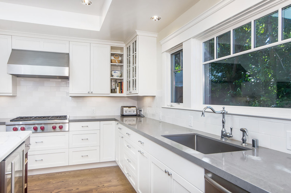 Photo of a transitional kitchen in San Francisco with shaker cabinets, stainless steel appliances, a single-bowl sink, white cabinets, quartz benchtops, white splashback and subway tile splashback.