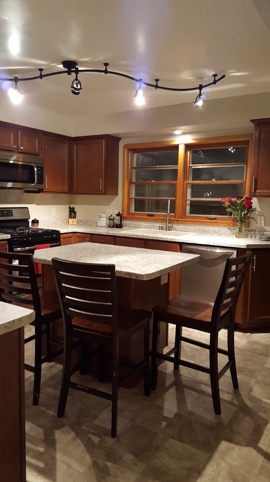 Inspiration for a mid-sized transitional l-shaped vinyl floor enclosed kitchen remodel with a drop-in sink, recessed-panel cabinets, medium tone wood cabinets, laminate countertops, stainless steel appliances and an island