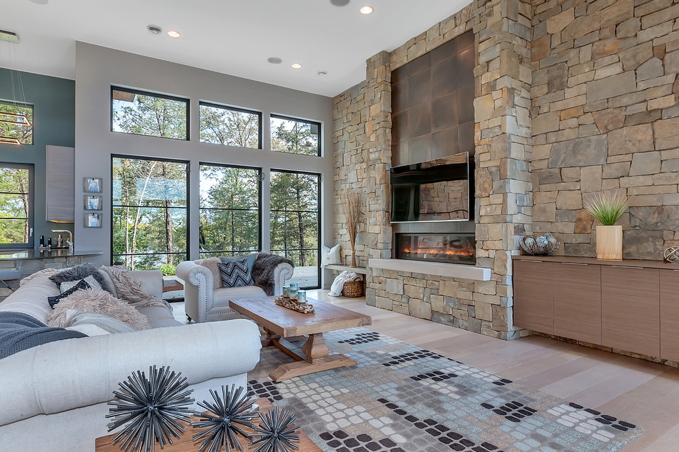 Photo of a large contemporary open concept family room in Minneapolis with grey walls, light hardwood floors, a metal fireplace surround, a wall-mounted tv, a ribbon fireplace and beige floor.