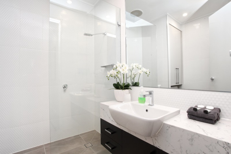 This is an example of a small modern master bathroom in Melbourne with flat-panel cabinets, black cabinets, an alcove shower, white tile, ceramic tile, white walls, ceramic floors, engineered quartz benchtops, grey floor, an open shower and white benchtops.
