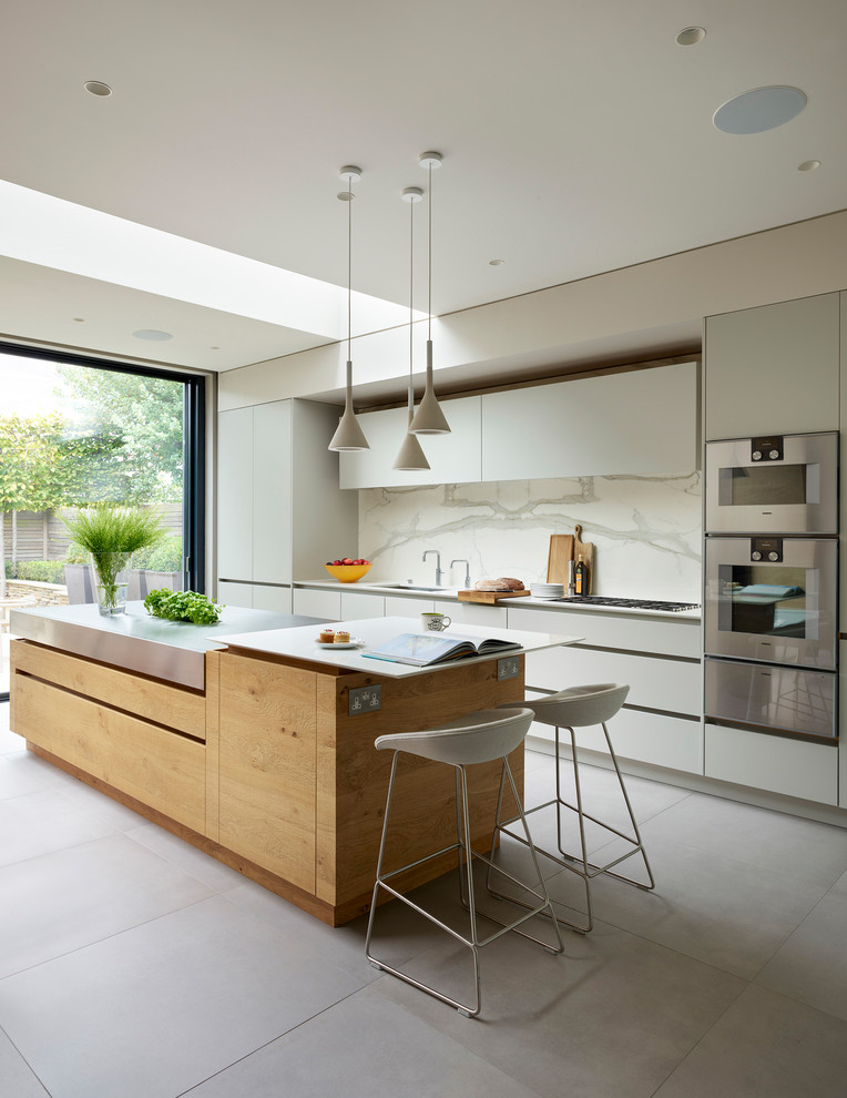 Photo of a large contemporary single-wall open plan kitchen in London with flat-panel cabinets, blue cabinets, solid surface benchtops, white splashback, with island, grey floor and white benchtop.