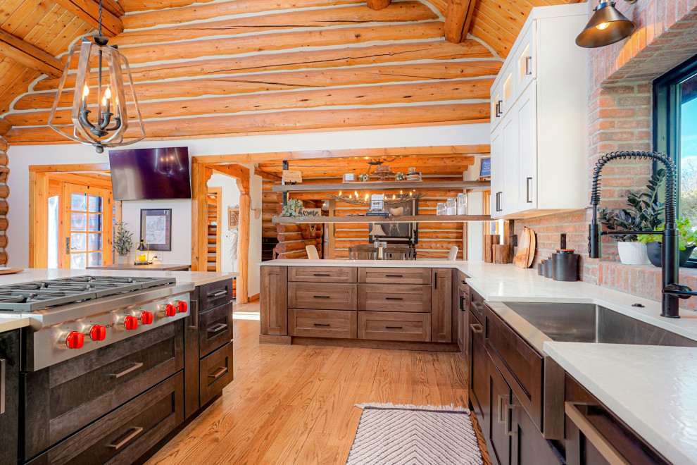 Inspiration for an expansive rustic u-shaped open plan kitchen with a belfast sink, shaker cabinets, dark wood cabinets, stainless steel appliances, an island and exposed beams.