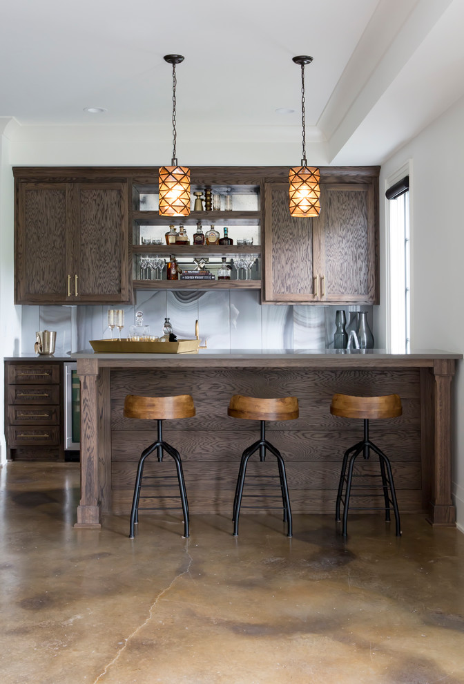 This is an example of a beach style single-wall wet bar in Nashville with shaker cabinets, dark wood cabinets, grey splashback, concrete floors and brown floor.