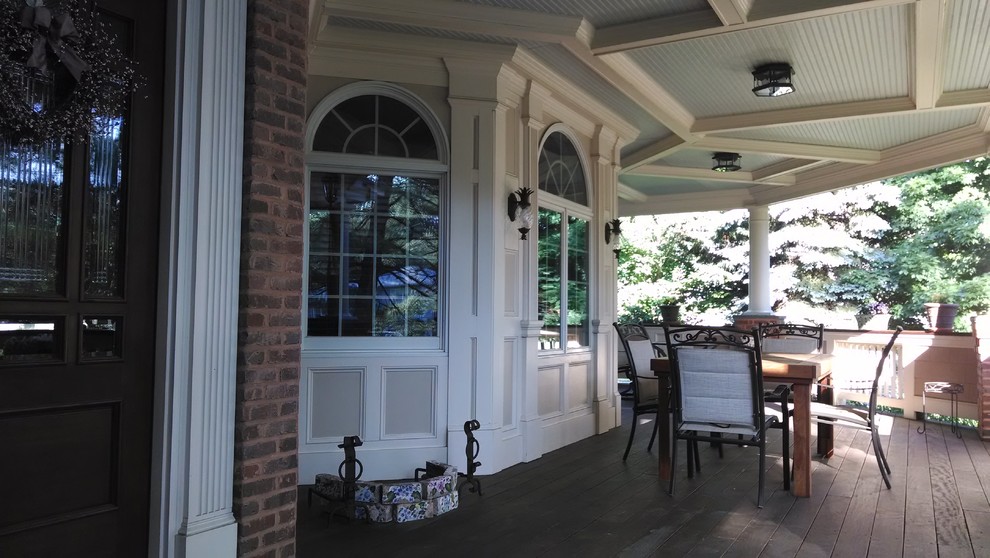 This is an example of a large traditional stone front porch design in New York with a roof extension.