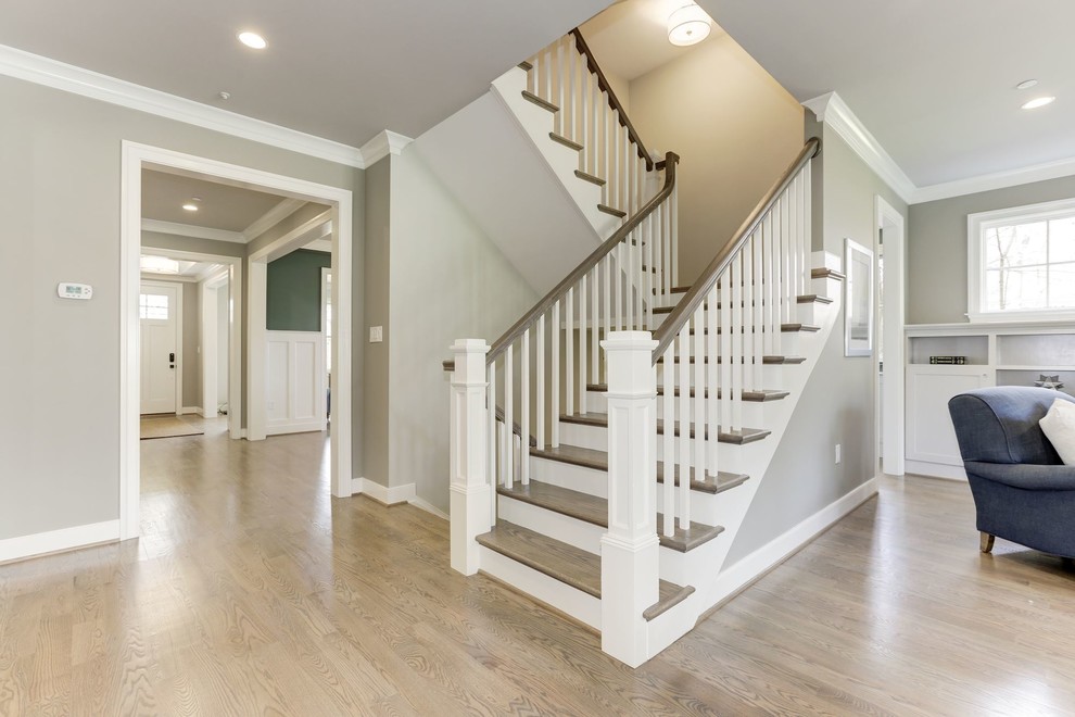 Photo of a large transitional wood u-shaped staircase in Other with painted wood risers and wood railing.