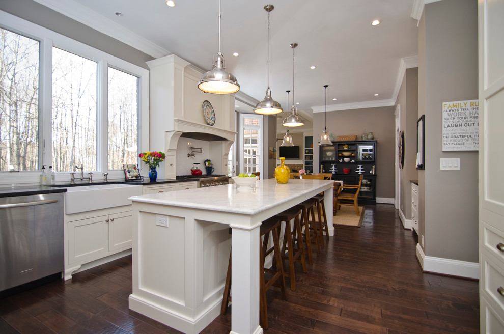 Design ideas for a traditional eat-in kitchen in DC Metro with a farmhouse sink, flat-panel cabinets, white cabinets, marble benchtops, white splashback, porcelain splashback and stainless steel appliances.