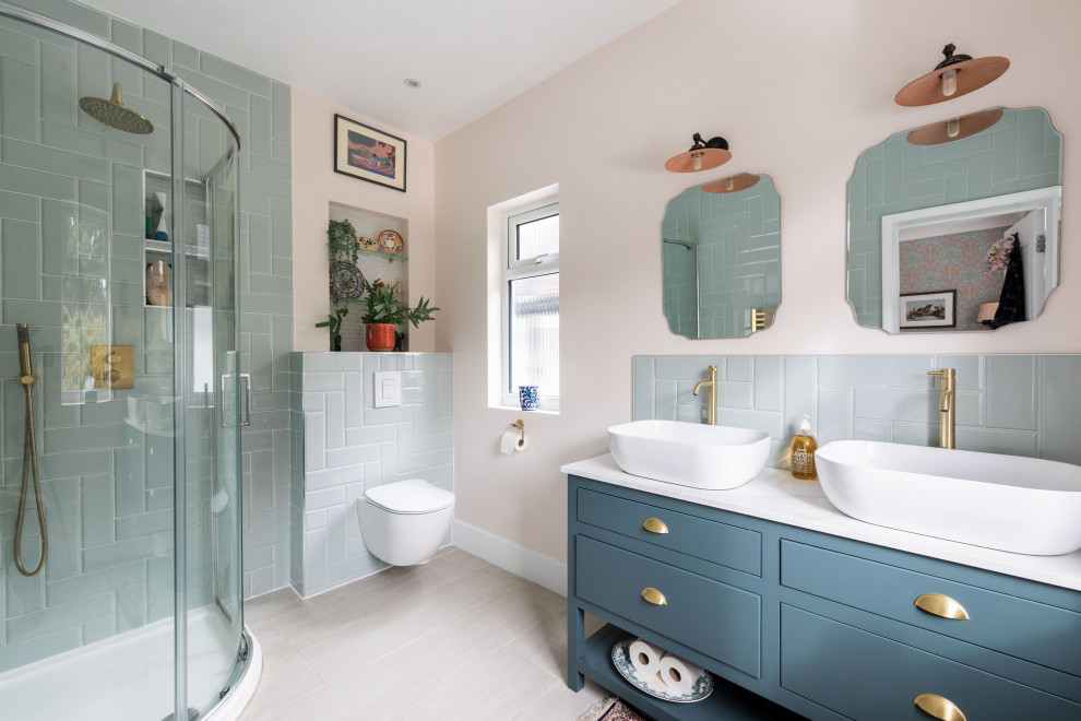 This is an example of a transitional bathroom in London with flat-panel cabinets, blue cabinets, a corner shower, blue tile, beige walls, a vessel sink, beige floor, a sliding shower screen, white benchtops, a double vanity and a freestanding vanity.