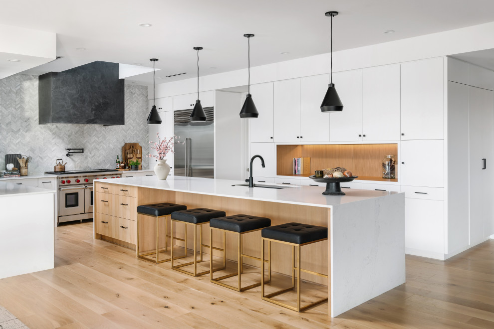 Inspiration for a large contemporary u-shaped eat-in kitchen in Austin with an undermount sink, flat-panel cabinets, white cabinets, quartz benchtops, white splashback, ceramic splashback, stainless steel appliances, light hardwood floors, with island, beige floor, white benchtop and timber.