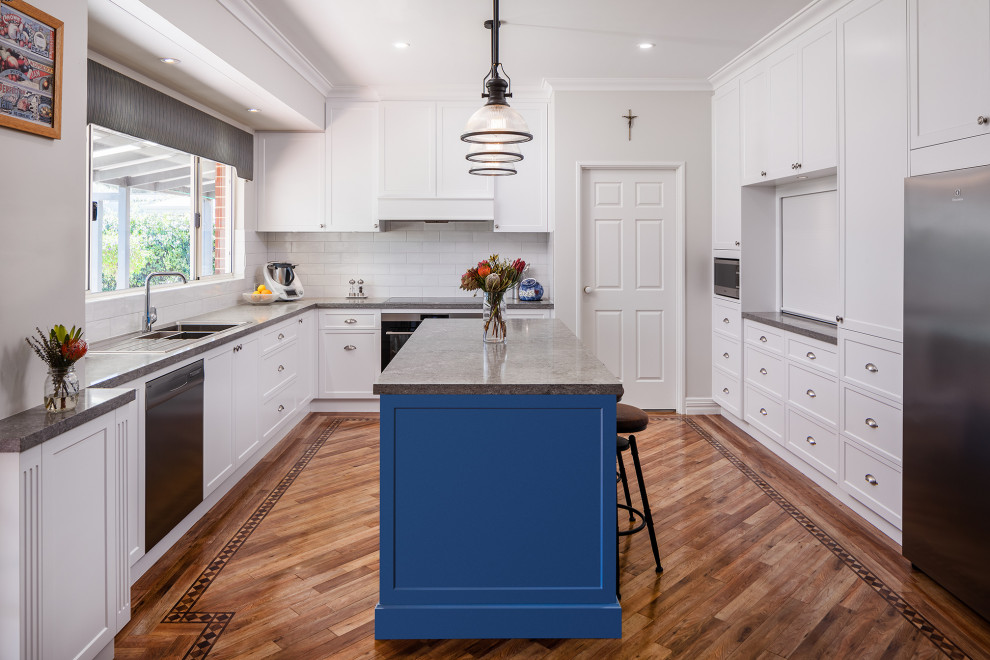 This is an example of a modern kitchen in Perth with shaker cabinets, white cabinets, quartz benchtops, white splashback, subway tile splashback, medium hardwood floors, with island and grey benchtop.