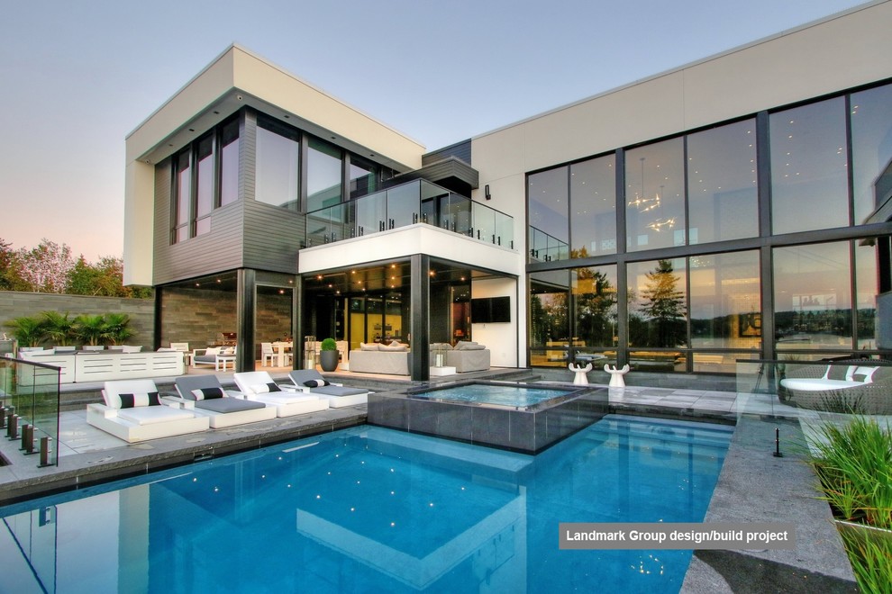 Example of a mid-sized minimalist backyard stone and rectangular infinity hot tub design