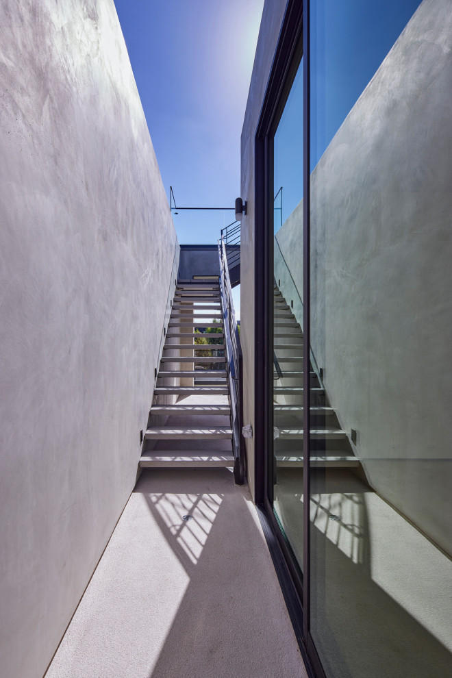 Medium sized modern concrete l-shaped mixed railing staircase in Los Angeles with open risers.