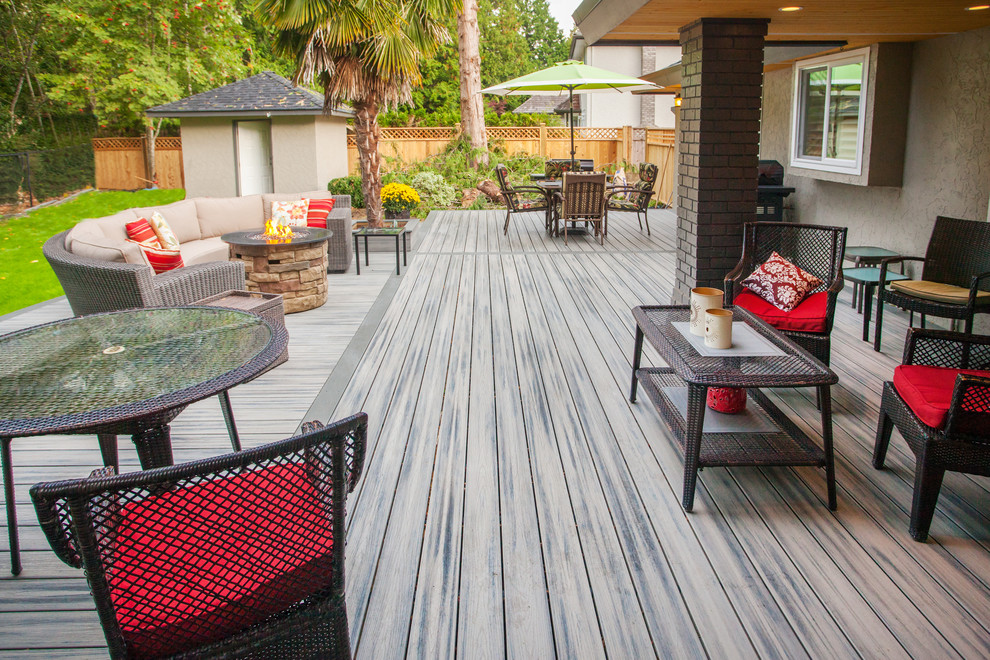 This is an example of an expansive modern backyard deck in Vancouver with a fire feature and no cover.