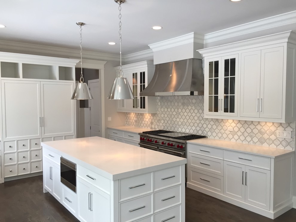 Design ideas for a mid-sized beach style u-shaped separate kitchen in Chicago with an undermount sink, shaker cabinets, white cabinets, solid surface benchtops, white splashback, porcelain splashback, stainless steel appliances, dark hardwood floors and with island.