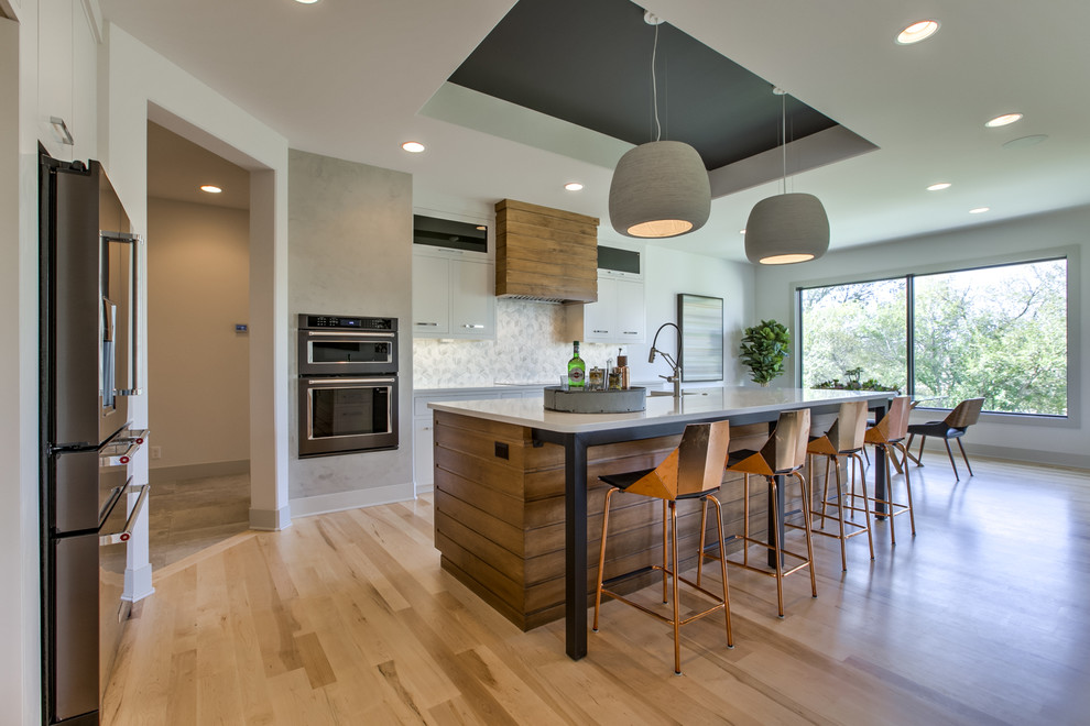 Midcentury kitchen in Omaha with quartz benchtops, ceramic splashback, black appliances and light hardwood floors.