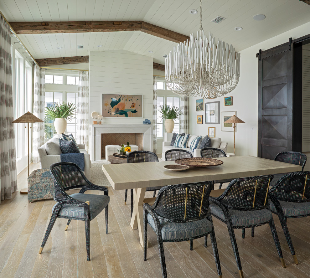 This is an example of a large beach style open plan dining in Other with white walls, painted wood floors, a standard fireplace, beige floor, exposed beam and planked wall panelling.