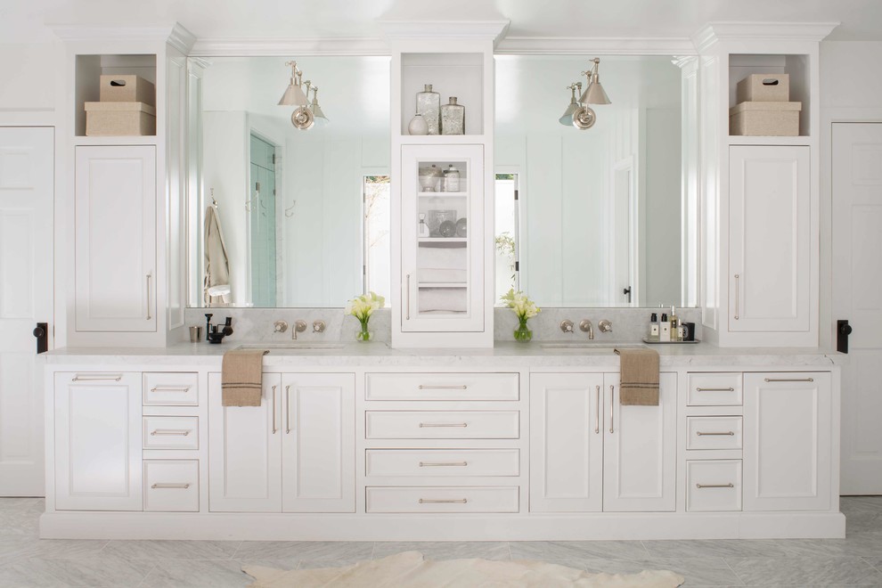 This is an example of a large country master bathroom in Los Angeles with beaded inset cabinets, white cabinets, a freestanding tub, an alcove shower, a two-piece toilet, white tile, marble, white walls, marble floors, a drop-in sink, marble benchtops, grey floor, a hinged shower door and white benchtops.
