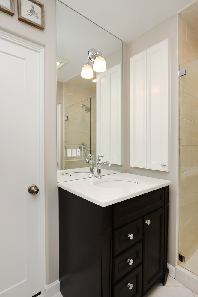 Small traditional 3/4 bathroom in Grand Rapids with recessed-panel cabinets, dark wood cabinets, an alcove shower, a one-piece toilet, beige walls, ceramic floors, an integrated sink, engineered quartz benchtops, beige floor and a hinged shower door.