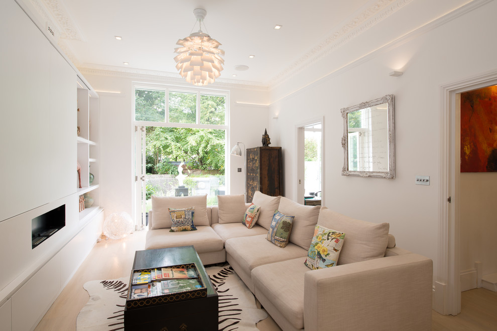 Scandinavian formal enclosed living room in London with white walls, light hardwood floors and a ribbon fireplace.