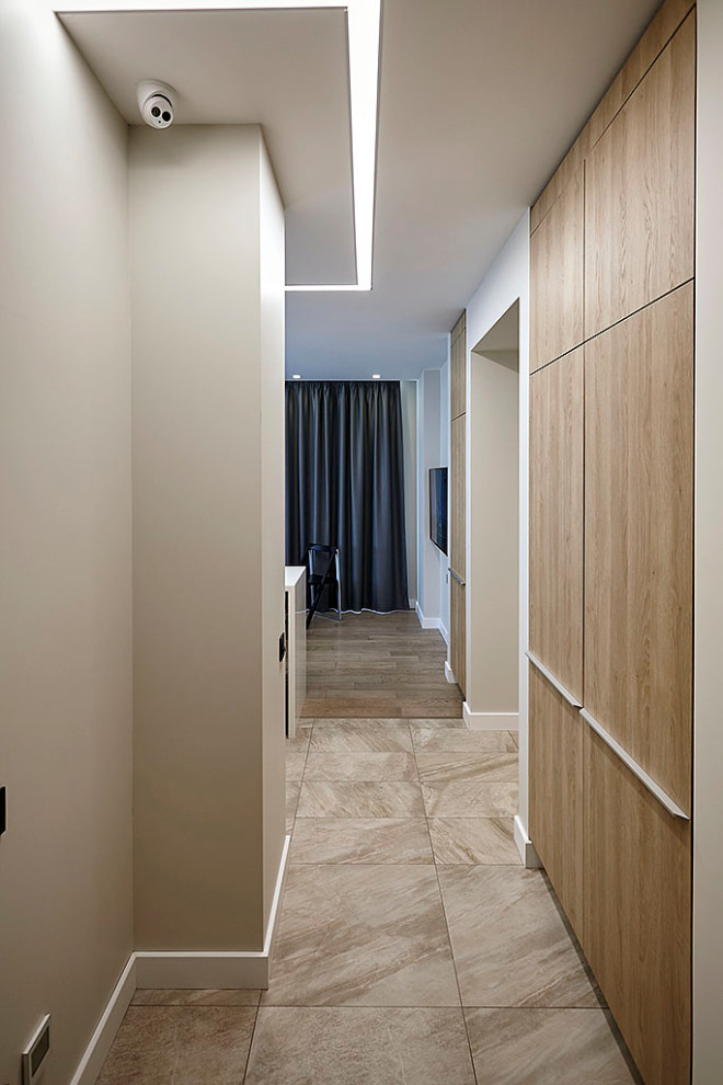 Стильный дизайн: коридор среднего размера: освещение в скандинавском стиле с бежевыми стенами, полом из керамогранита и коричневым полом - последний тренд
