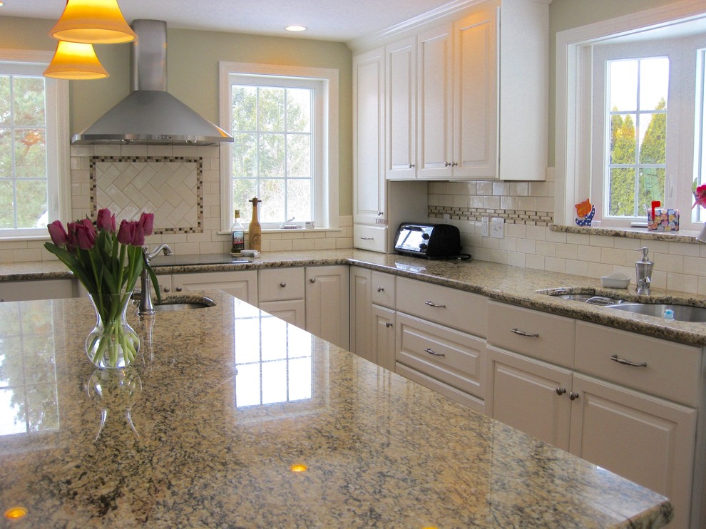 Transitional u-shaped medium tone wood floor eat-in kitchen photo in Boston with an undermount sink, raised-panel cabinets, white cabinets, granite countertops, white backsplash, ceramic backsplash, stainless steel appliances, an island and beige countertops
