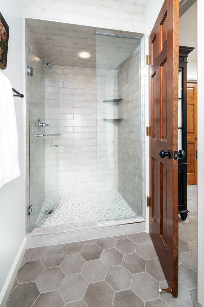 Mid-sized country master bathroom in Omaha with shaker cabinets, white cabinets, a freestanding tub, an alcove shower, white tile, ceramic tile, white walls, porcelain floors, an undermount sink, marble benchtops, grey floor, a hinged shower door and white benchtops.