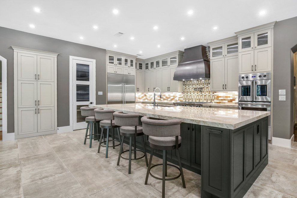 This is an example of a large transitional l-shaped eat-in kitchen in Houston with recessed-panel cabinets, beige cabinets, brown splashback, glass tile splashback, stainless steel appliances, with island, beige benchtop, an undermount sink, cement tiles, grey floor and quartzite benchtops.