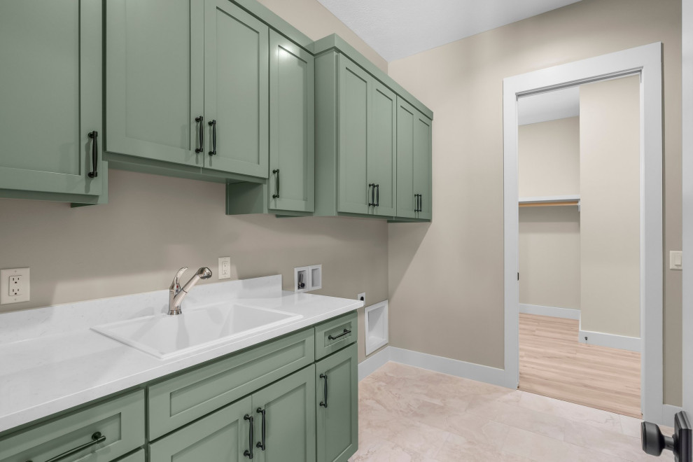 Large arts and crafts galley porcelain tile and beige floor dedicated laundry room photo with a drop-in sink, shaker cabinets, green cabinets, quartz countertops, beige walls, a side-by-side washer/dryer and white countertops